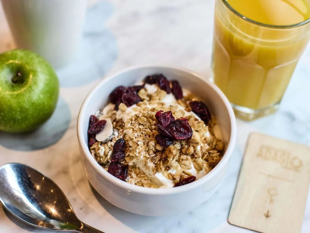a bowl of cereal with raisins and a glass of orange juice at Aparthotel Adagio Edinburgh Royal Mile in Edinburgh